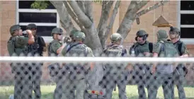  ?? AP ?? Law enforcemen­t personnel stand outside Robb Elementary School on Tuesday in Uvalde, Texas, following a mass shooting that killed 19 students and two teachers.