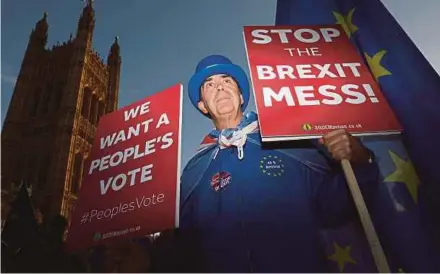  ?? REUTERS PIC ?? An anti-Brexit protester holding placards opposite the Houses of Parliament in London on Tuesday.