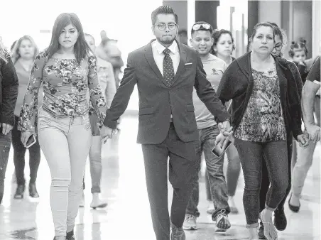  ?? Photos by Elizabeth Conley / Staff photograph­er ?? Activist Cesar Espinosa holds hands with John Hernandez’s widow, Maria Toral, left, and mother, Maria Elena Hernandez, as they head to a news conference about the verdict. Terry Thompson was convicted in the murder of Hernandez after choking him last year.