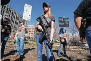  ??  ?? Brooke Wang of Plano carries a rifle while joining a small group of counter-demonstrat­ors.