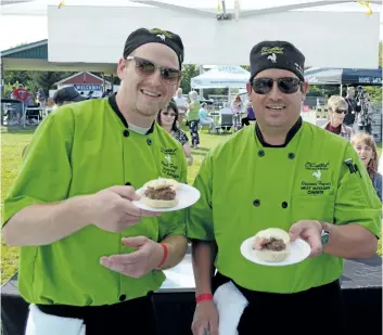  ?? PHOTOS BY DAVE JOHNSON/WELLAND TRIBUNE ?? Paul Fegj, left, and Raymond Haymes of Churchhill Natural Meats hold up chipotle cheddar bison sliders with doublesmok­ed wild boar bacon and a rosette of garlic aioli Saturday at the first-ever Pelham Sliderfest put on by the Fonthill Lions.