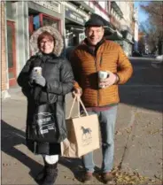  ?? LAUREN HALLIGAN — THE SARATOGIAN ?? Robert and Doreen Sciulla of Saratoga Springs clutch hot coffees in one hand and shopping bags in the other on Black Friday morning while out shopping on Broadway in Saratoga Springs.