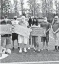  ?? CAPITAL GAZETTE PAUL W. GILLESPIE/ ?? Bob Hough’s brother John Hough, left, father Richard Hough, center, and sister Tara Rose, right, hold plaques surrounded by other family and school officials Wednesday. St. Mary’s and Severn School at halftime of the JV girls lacrosse game honored the late Capital Gazette high school sports editor Bob Hough, who died Oct. 31 at age 46.