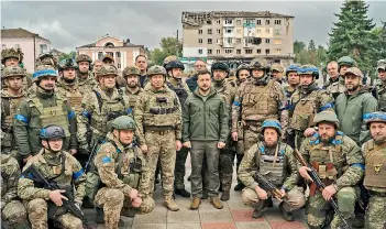  ?? — AP ?? Ukrainian President Volodymyr Zelenskyy poses for a photo with soldiers after attending a national flag-raising ceremony in the freed Izium, Ukraine, on Wednesday.