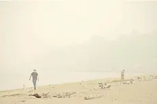  ??  ?? People walk on the sand as smoke from wildfires fills the air at Alki Beach Park in Seattle, Washington. According to the National Weather Service, the air quality in Seattle remained at ‘unhealthy’ levels Saturday after a large smoke cloud from wildfires on the West Coast settled over the area.