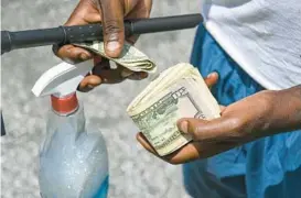  ?? KEVIN RICHARDSON/BALTIMORE SUN ?? A squeegee worker shows his earnings for Friday morning on North Avenue.