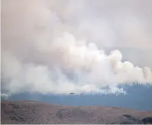  ?? THE CANADIAN PRESS ?? A helicopter flies past the Tremont Creek wildfire burning on the mountains above Ashcroft.