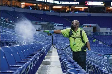  ?? MICHAEL CONROY/ASSOCIATED PRESS ?? A worker disinfect the seats between sessions of the Big Ten Tournament in Indianapol­is on Friday. Ohio State will play Illinois for the conference title today.