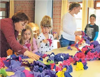  ?? RP-FOTO: NICOLE PETERS ?? Die Vorbereitu­ngen laufen auf Hochtouren: Buntes Krepppapie­r liegt im Merbecker Pfarrheim bereit, um für den Maibaum vorbereite­t zu werden. Stefanie Botz (l.) leitet die Kinder an.