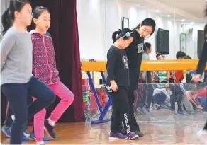  ?? PHOTOS PROVIDED TO CHINA DAILY ?? Irish step dance enthusiast Wu Dan teaches kids of the elementary department of Beijing Chenjinglu­n High School to do the steps of tita dancing.