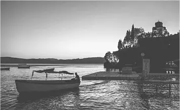  ??  ?? Piloting a boat in front of the St John Kaneo Church on the Lake Ohrid.