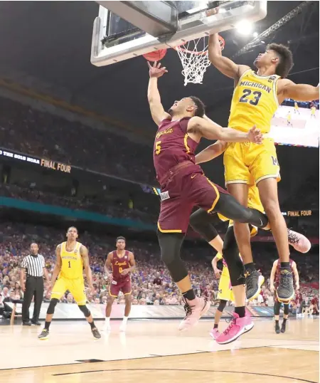  ?? GETTY IMAGES ?? Loyola’s Marques Townes shields himself from Michigan’s Ibi Watson as he puts up a shot Saturday in San Antonio.