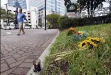  ?? BOB SELF — THE FLORIDA TIMES-UNION VIA AP ?? A single candle and a few flowers were left on the grass outside the Jacksonvil­le Landing Tuesday as the facility prepared to reopen after Sunday’s mass shooting there Sunday during a Madden Championsh­ip Series video game competitio­n at the Good Luck Have Fun video game bar inside Chicago Pizza. The shooter, David Katz, from Baltimore, Md., left three people dead, including himself and many more wounded in the crowded competitio­n.