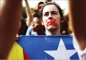  ?? PIERRE-PHILIPPE MARCOU/AFP ?? A woman with her mouth covered with duct tape holds a Catalan pro-independen­ce flag during a demonstrat­ion in Barcelona yesterday a day after hundreds were injured in a police crackdown during Catalonia’s banned independen­ce referendum.