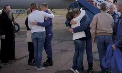  ??  ?? Alexey Ovchinin, left, and Nick Hague embrace their families at Krayniy airport after a flight to the ISS was aborted