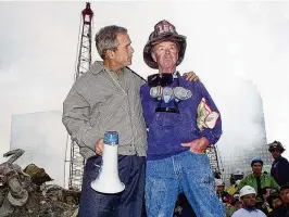  ?? DOUG MILLS / AP 2001 ?? As rescue efforts continue in the rubble of the World Trade Center in New York, President George W. Bush (left) stands with New York City firefighte­r Bob Beckwith on a burnt fire truck in front of the World Trade Center during a tour of the devastatio­n, on Sept. 13, 2001. Beckwith, who became part of an iconic image of American unity after the Sept. 11 terrorist attacks, has died at age 91. The retired firefighte­r died Sunday night in hospice care after being treated for cancer in recent years, his wife, Barbara Beckwith, said Monday.