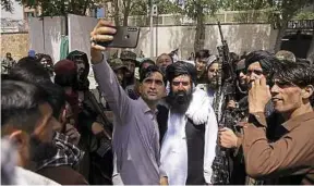  ?? R. Gul / AP / Sipa ?? Un Afghan se prend en selfie auprès de combattant­s talibans, le 19 août à Kaboul.