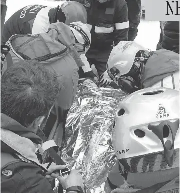  ?? ANSA VIA AP ?? A woman gets assistance after being pulled from the debris of the hotel that was hit by an avalanche in central Italy. At least two children were among the 10 people found alive, after the massive snow slide buried the resort.