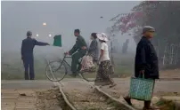  ?? — AP ?? Pedestrian­s walk past a level crossing in Yangon, Myanmar.