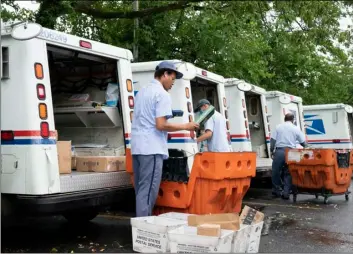  ?? AP Photo/J. Scott Applewhite ?? In this July 31 file photo, letter carriers load mail trucks for deliveries at a U.S. Postal Service facility in McLean, Va.