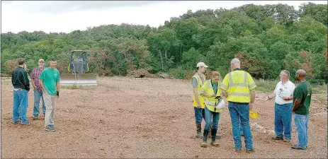  ?? Keith Bryant/The Weekly Vista ?? Arkansas Department of Environmen­tal Quality staff, along with Brown’s Tree Care staff, examine the burning stump dump site. Some steam rises from the ground, but very little smoke is present.