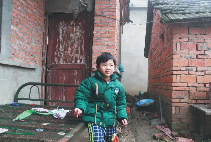  ?? ZHU LIXIN / CHINA DAILY ?? Zhou Junhao, 6, lives with his grandmothe­r, Song Jinlan, a widow, in Fuyang’s Wuli village, Anhui province. Zhou’s parents live and work in Hangzhou and send about 1,000 yuan a month to Song for child care and other expenses.