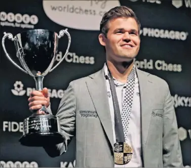  ??  ?? TRIUNFADOR. Magnus Carlsen posa con la copa y la medalla que le acreditan como campeón mundial.