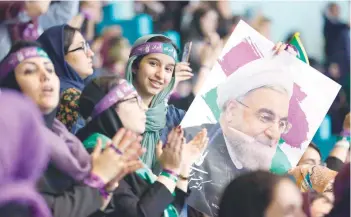  ?? — AFP ?? Supporters of Iranian President and presidenti­al candidate Hassan Rouhani hold up his portrait during a campaign rally in the capital Tehran on Saturday.