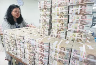  ??  ?? A Bangkok Bank employee gathers stacks of thousand-baht banknotes. A senior BoT official said banks have a sufficient capital buffer in the event of higher past-due payments and debt restructur­ing.