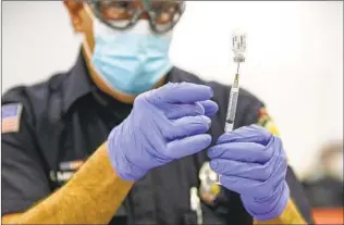  ?? EDUARDO CONTRERAS U-T PHOTOS ?? Firefighte­r/paramedic Mitch Mendler prepares a syringe for a recipient at the San Diego FireRescue Department’s training facility. Three hundred were expected to be vaccinated.