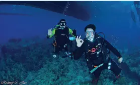  ??  ?? DIVERS pose for OK sign as they dive through Coral Garden in Barangay Tibanban, Governor Generoso