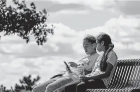  ?? Morry Gash / Associated Press ?? Savannah Brown and Glendy Stollberg use their phone in Kilbourn Reservoir Park last week in Milwaukee. The city of Milwaukee has placed wireless broadband hot spots in the park during the pandemic.