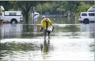  ?? MARTA LAVANDIER — THE ASSOCIATED PRESS ?? A man carries his golf bag and shoes through a flooded neighborho­od Friday in Fort Lauderdale, Fla.