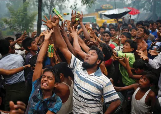  ??  ?? ROHINGYA REFUGEES reach out their hands to grab aid packages in Cox’s Bazar, Bangladesh, on Sunday.