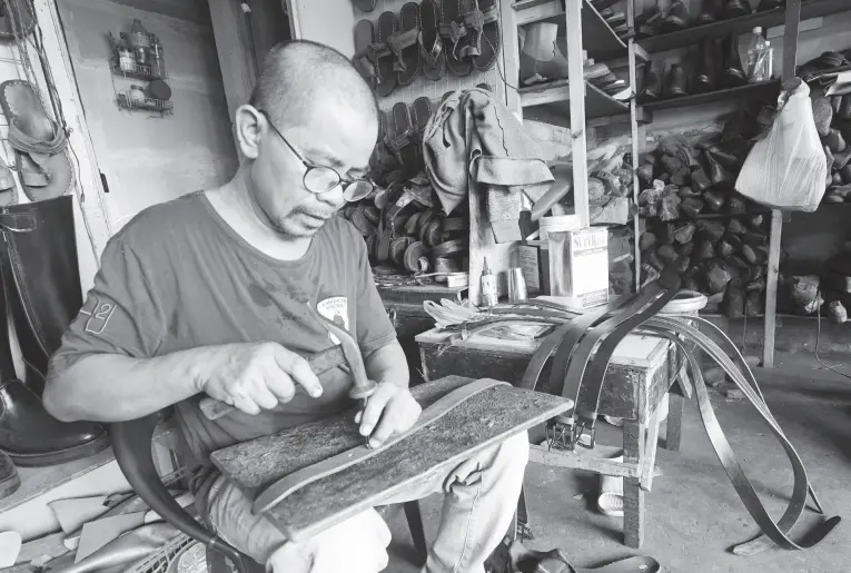  ?? (PNA photo by Ben Briones) ?? LEATHER GOODS. Aliano Genelza, Jr., 48, punches some holes in a leather belt inside his shop on Juan Luna Street, Gagalangin, Tondo, Manila on Wednesday (May 4, 2022). The belts cost between PHP500 and PHP1,500 each depending on the type of material.