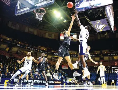  ?? STAFF PHOTOS BY ROBIN RUDD ?? UTC’S David Jean-Baptiste (3) shoots over UNC Greensboro’s Angelo Allegri during Saturday’s SoCon game at McKenzie Arena. Jean-Baptiste scored 13 points for the Mocs, who lost 74-66 as they were unable to hold on to their lead late in the second half.