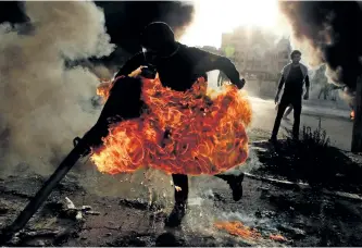  ?? ABBAS MOMANI/GETTY IMAGES ?? A Palestinia­n protester runs after catching fire during clashes with Israeli troops at a protest of U.S. President Donald Trump’s decision to recognize Jerusalem as the capital of Israel, near near the West Bank city of Ramallah.