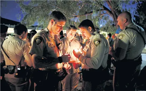  ??  ?? Police officers hold candles during a vigil for the victims of a mass shooting at the Route 91 Harvest Country Music Festival in Las Vegas.