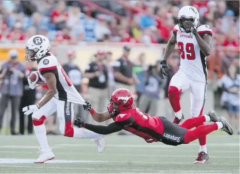  ?? MIKE RIDEWOOD/THE CANADIAN PRESS ?? Calgary’s Ciante Evans tries to bring down Ottawa’s Diontae Spencer during recent CFL action. With the current divisional imbalance in the CFL, some are calling for a change in the East-West playoff format.