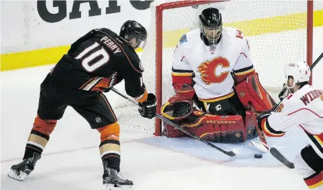  ?? Jae C. Hong/ The As ociated Press ?? The Anaheim Ducks’ Corey Perry scores on Calgary Flames goalie Jonas Hiller in the second period Thursday in Anaheim.