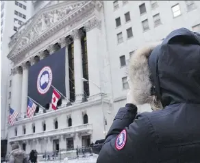  ?? THE CANADIAN PRESS ?? A woman wearing a Canada Goose coat stops to photograph the company’s banner as the company launched its IPO at the New York Stock Exchange, earlier this year.