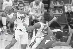  ?? MICHAEL CONROY — THE ASSOCIATED PRESS ?? Baylor guard Jared Butler (12) passes over teammate guard Adam Flagler (10) and Houston forward Justin Gorham (4) during the first half of their Final Four semifinal on Saturday at Lucas Oil Stadium in Indianapol­is.