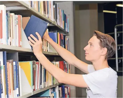  ?? FOTO: JUDITH MICHAE-
LIS/DPA ?? Alle Lehrbücher im Blick: Jakob Kemper muss sich als studentisc­he Hilfskraft mit der Literatur für ein Seminar auskennen.