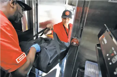  ?? Photos by Michael Macor / The Chronicle ?? Zume Captain Skylar Morris (left), the truck crew “pielot,” hands a pizza for delivery to driver Deepak Dabadi.