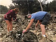  ?? AP Photo/Haven Daley ?? ■ Kevin Conant and his wife, Nikki, sift through debris of their burnt home and business Conants Wine Barrel Creations after the Glass/Shady fire engulfed it Wednesday in Santa Rosa, Calif. The Conants escaped with their lives, which we are grateful for, but they barely made it out with the clothes on their backs in the wake of the fire. The Glass and Zogg fires are among nearly 30 wildfires burning in California.