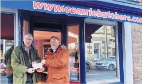  ?? ?? Donation Murray Lauchlan of David Comrie & Son butchers presents a cheque to Rev Craig Dobney, who collected it on behalf of Christian Aid