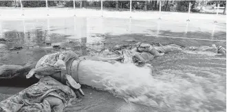  ?? Mayra Cruz ?? A hose is weighed down by sandbags as it pumps out water from the Hewlett Packard Enterprise building next to Lone Star College University Park’s Enterprise and Manufactur­ing Institute.