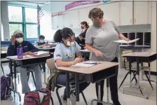  ?? John Moore / Getty Images ?? Eighth-grade math teacher Leeann Heller talks to a student at Scofield Magnet Middle School, where absenteeis­m has been 2%.