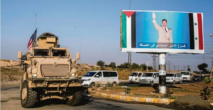  ?? Fotos: Baderkhan Ahmad, dpa; Cedric Rehman (2) ?? Auch die Amerikaner sind wieder da: Konvoi des US-Militärs nahe der Stadt Qamischli in Nordostsyr­ien. Das Plakat rechts zeigt den syrischen Machthaber Baschar al-Assad.