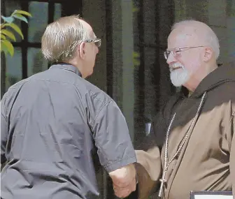  ?? STAFF PHOTOS BY ANGELA ROWLINGS ?? SCANDAL: Cardinal Sean O’Malley, above, greets a priest as he arrives at St. Julia Parish yesterday. Ex-Catholic priest Robert Hoatson, below, demonstrat­es outside.